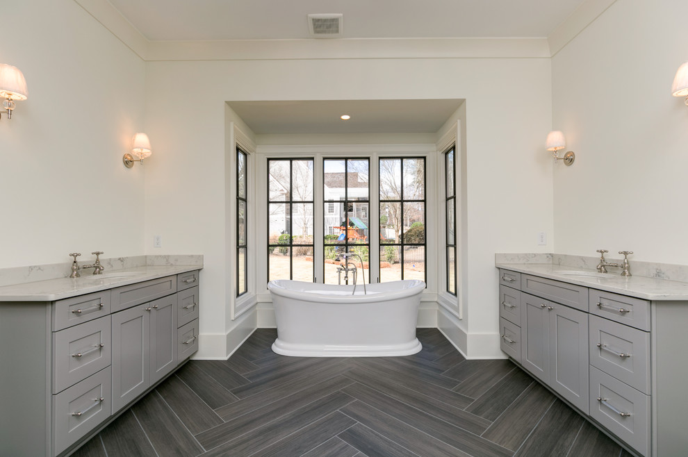 На фото: большая главная ванная комната в стиле кантри с фасадами в стиле шейкер, серыми фасадами, отдельно стоящей ванной, серой плиткой, белыми стенами, полом из керамогранита, врезной раковиной и столешницей из гранита