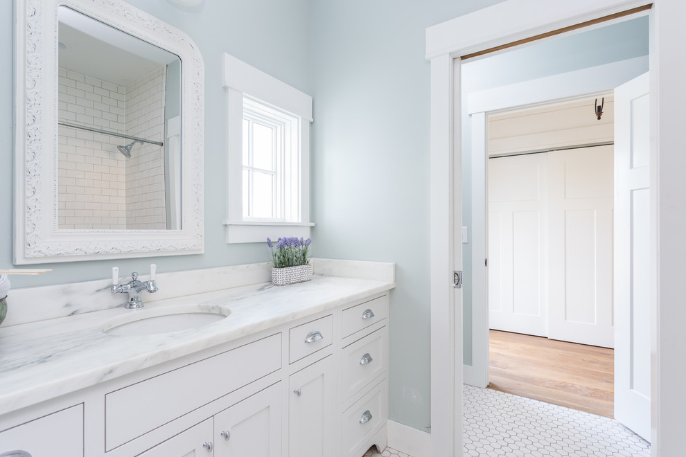 Immagine di una stanza da bagno country di medie dimensioni con ante in stile shaker, ante bianche, piastrelle bianche, pareti blu, pavimento con piastrelle in ceramica e top in marmo