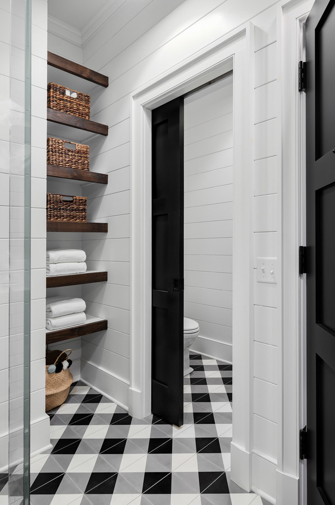 Mittelgroßes Country Badezimmer mit Wandtoilette mit Spülkasten, weißen Fliesen, weißer Wandfarbe, Keramikboden und buntem Boden in New York