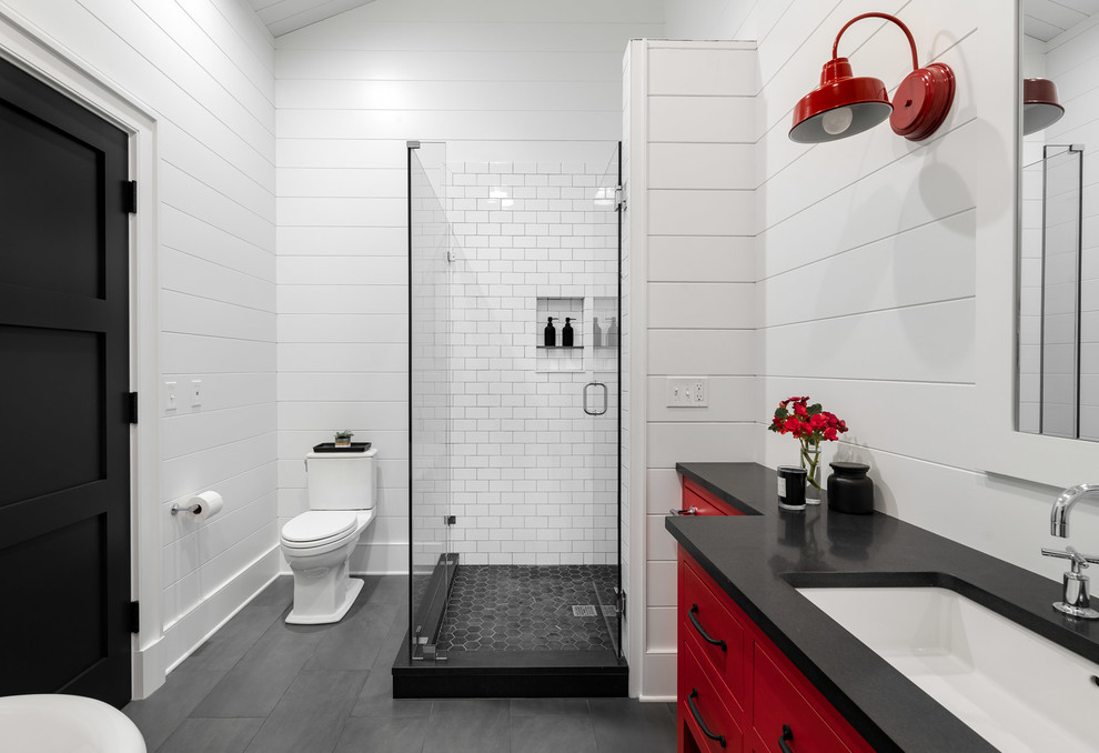 Example of a large cottage white tile and subway tile slate floor and gray floor corner shower design in New York with flat-panel cabinets, red cabinets, a two-piece toilet, white walls, an undermount sink, concrete countertops, black countertops and a hinged shower door