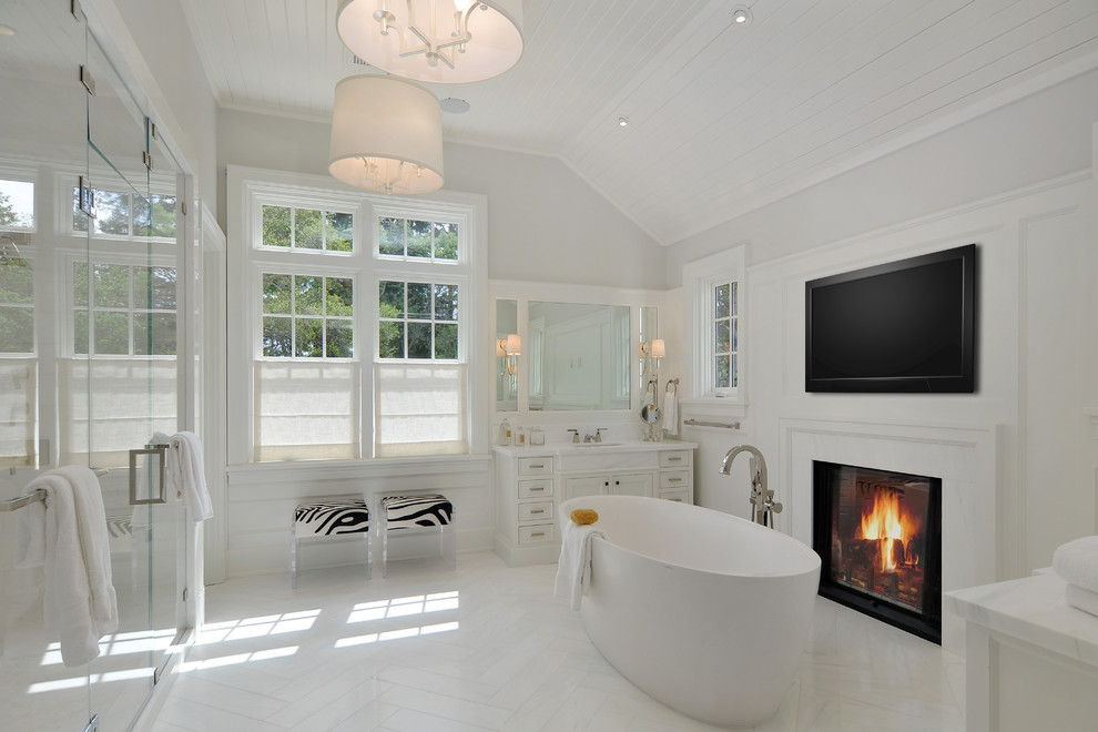 Lantlig inredning av ett en-suite badrum, med vita skåp, ett fristående badkar, grå väggar, ett undermonterad handfat och dusch med gångjärnsdörr