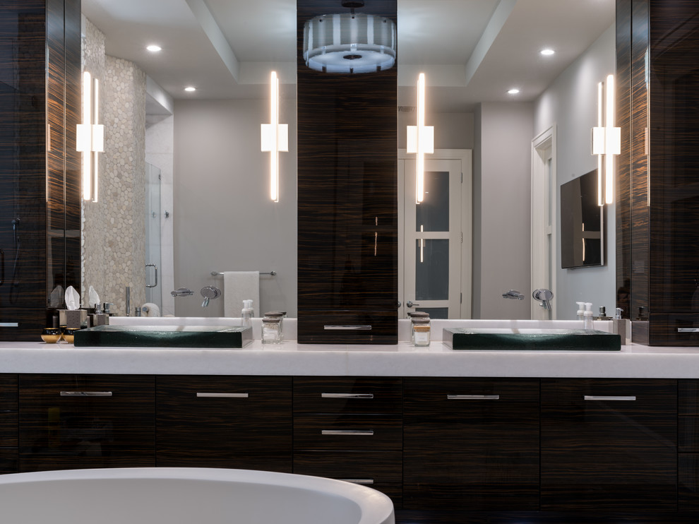 This is an example of a large modern ensuite bathroom in Miami with flat-panel cabinets, dark wood cabinets, a freestanding bath, a double shower, grey tiles, marble tiles, marble flooring, a vessel sink, marble worktops, beige walls, grey floors and a hinged door.