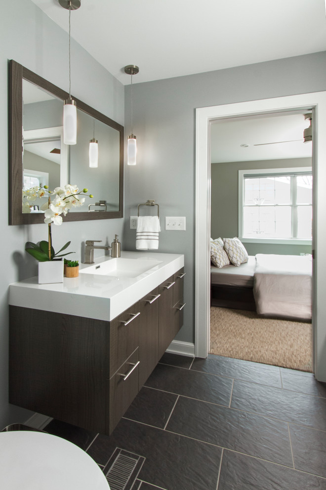 This is an example of a medium sized classic ensuite bathroom in Minneapolis with grey walls, grey tiles, flat-panel cabinets, dark wood cabinets, an alcove bath, a shower/bath combination, a two-piece toilet, an integrated sink, solid surface worktops, stone tiles and slate flooring.
