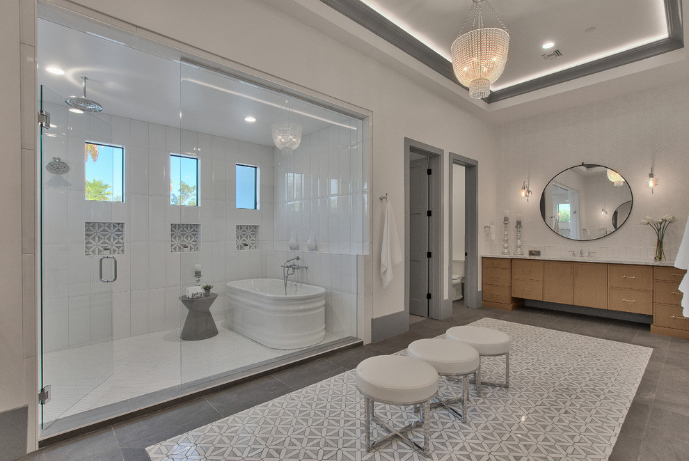 На фото: главная ванная комната в стиле неоклассика (современная классика) с фасадами цвета дерева среднего тона, отдельно стоящей ванной, душевой комнатой, белой плиткой, белыми стенами, серым полом, душем с распашными дверями и белой столешницей с