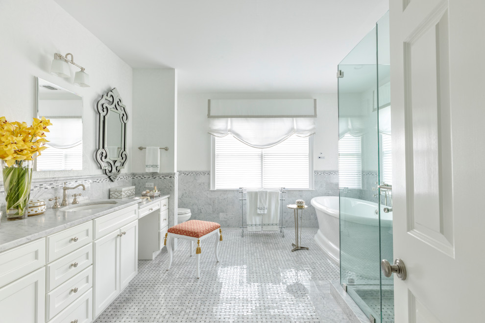Inspiration for an ensuite bathroom in New York with recessed-panel cabinets, white cabinets, a freestanding bath, a corner shower, grey tiles, white walls, mosaic tile flooring, a submerged sink, white floors, a hinged door and grey worktops.