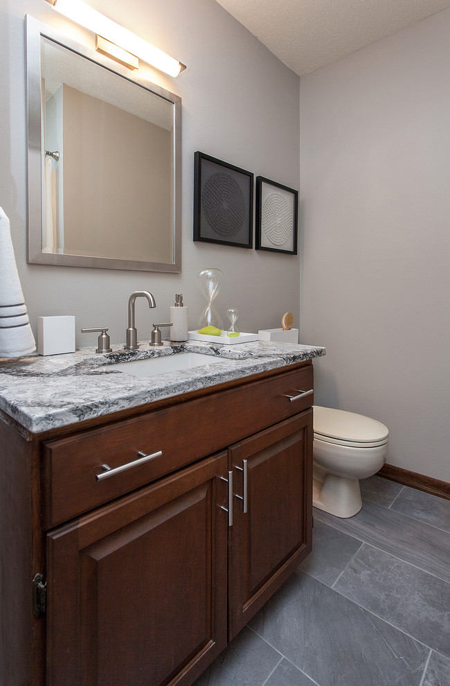 Example of a mid-sized 1960s gray tile and porcelain tile porcelain tile tub/shower combo design in Other with an undermount sink, raised-panel cabinets, medium tone wood cabinets, a one-piece toilet, white walls and quartzite countertops