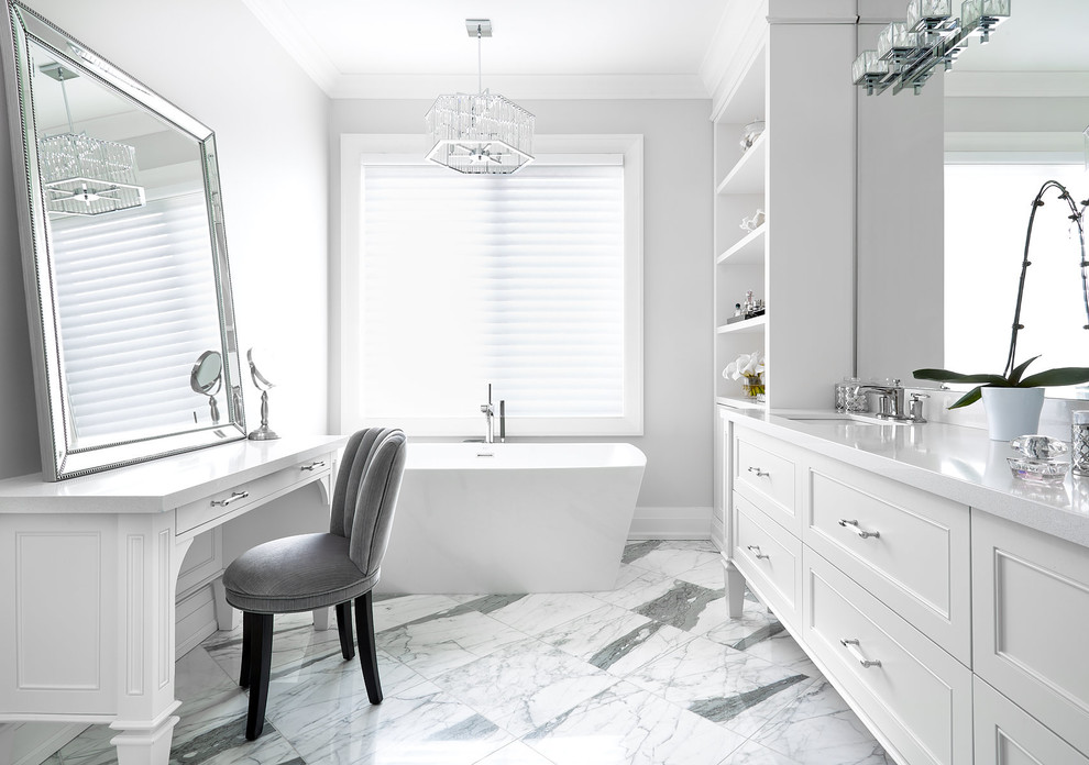 Klassisk inredning av ett stort vit vitt en-suite badrum, med luckor med infälld panel, vita skåp, ett fristående badkar, grå väggar, marmorgolv, ett undermonterad handfat, bänkskiva i kvarts och grått golv