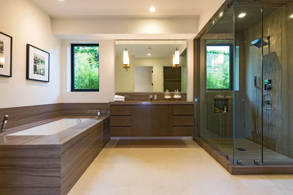 На фото: большая главная ванная комната в современном стиле с плоскими фасадами, темными деревянными фасадами, полновстраиваемой ванной, угловым душем, коричневой плиткой, белыми стенами, керамогранитной плиткой, полом из керамогранита, врезной раковиной, коричневой столешницей и окном