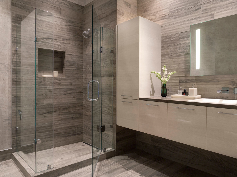 Example of a mid-sized minimalist master gray tile and ceramic tile ceramic tile and gray floor wet room design in San Francisco with flat-panel cabinets, a wall-mount toilet, gray walls, a drop-in sink, solid surface countertops and a hinged shower door