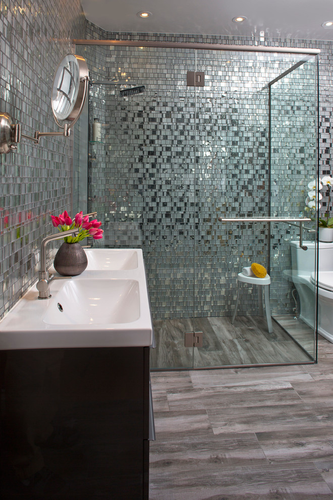 Immagine di una grande stanza da bagno padronale minimalista con lavabo integrato, ante lisce, ante grigie, doccia a filo pavimento, piastrelle grigie, piastrelle di vetro, pareti grigie, pavimento in travertino e WC a due pezzi