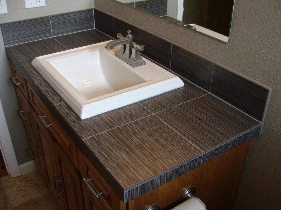 Esempio di una piccola stanza da bagno minimalista con lavabo da incasso, ante con riquadro incassato, ante in legno scuro, top piastrellato, piastrelle nere, piastrelle in gres porcellanato e pavimento in gres porcellanato