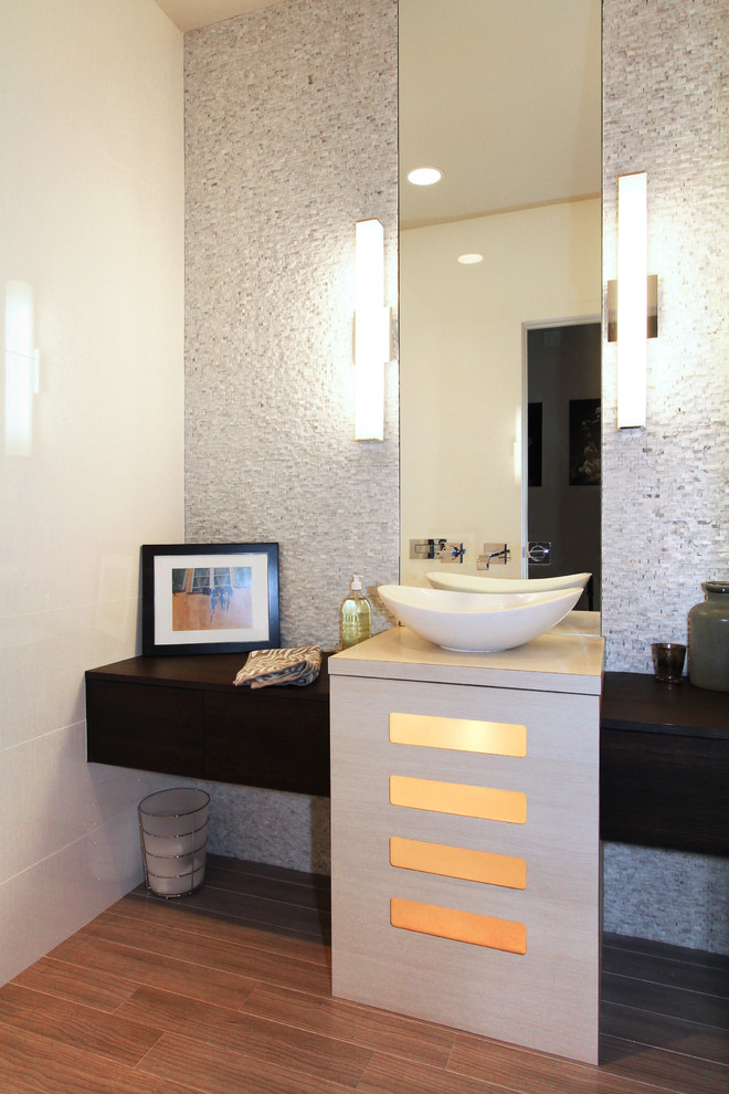 Modelo de cuarto de baño contemporáneo con lavabo sobreencimera, armarios con paneles lisos, puertas de armario de madera en tonos medios, baldosas y/o azulejos blancos, paredes beige y suelo de madera oscura