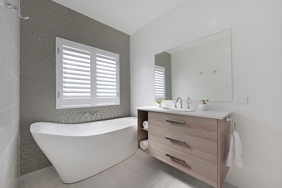 Example of a mid-sized trendy master white tile and ceramic tile ceramic tile and beige floor bathroom design in Townsville with flat-panel cabinets, light wood cabinets, a drop-in sink and quartz countertops