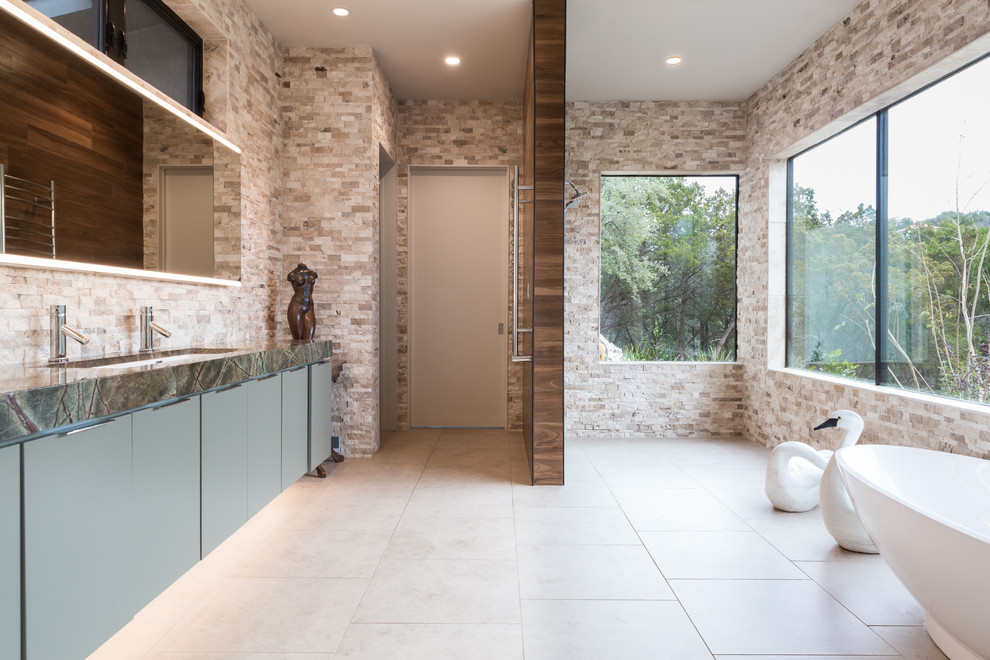 Idee per una stanza da bagno design con ante lisce, ante grigie, vasca freestanding, piastrelle beige, piastrelle in pietra, lavabo sottopiano, pavimento beige e top verde