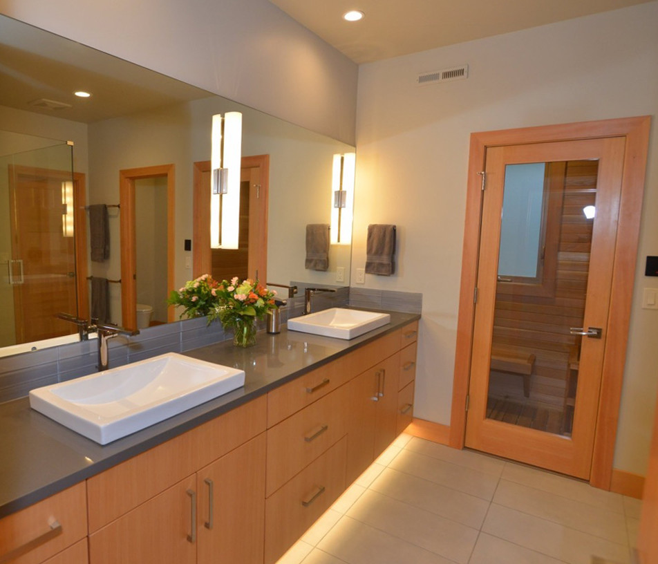 Стильный дизайн: главная ванная комната в современном стиле с плоскими фасадами, светлыми деревянными фасадами, угловым душем, унитазом-моноблоком, серыми стенами, полом из керамогранита, настольной раковиной, столешницей из искусственного кварца, серым полом и душем с распашными дверями - последний тренд