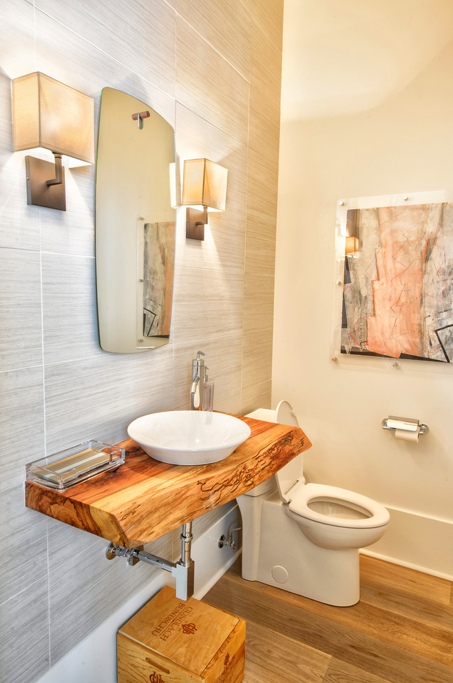 Kleines Modernes Duschbad mit Toilette mit Aufsatzspülkasten, grauer Wandfarbe, Aufsatzwaschbecken, Waschtisch aus Holz, braunem Holzboden und beigem Boden in New Orleans