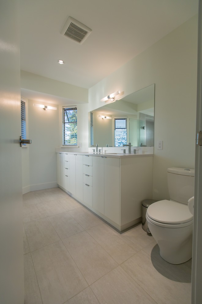 Inredning av ett modernt badrum med dusch, med släta luckor, vita skåp, en toalettstol med hel cisternkåpa, vita väggar, klinkergolv i porslin, ett undermonterad handfat, beiget golv och dusch med gångjärnsdörr