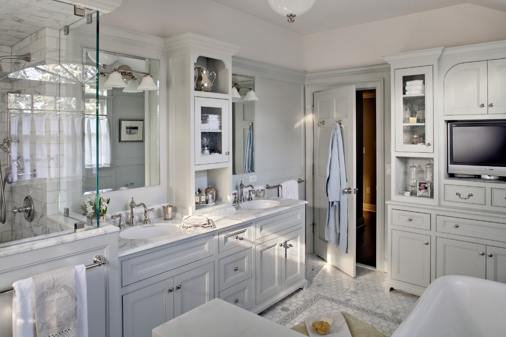 Immagine di una stanza da bagno padronale tradizionale con lavabo sottopiano, vasca freestanding, consolle stile comò, ante grigie, top in marmo, piastrelle grigie e piastrelle in pietra