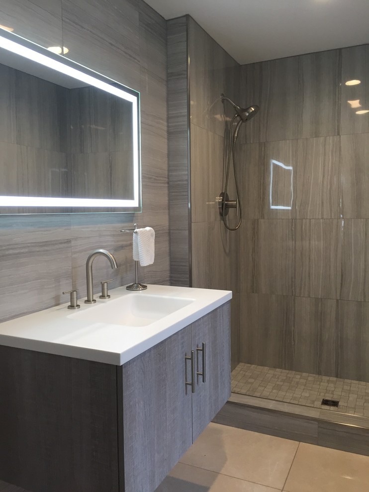 Exemple d'une salle de bain moderne de taille moyenne avec un placard à porte plane, des portes de placard grises, WC à poser, un carrelage gris, des carreaux de porcelaine, un mur gris, un sol en calcaire, un lavabo intégré, un plan de toilette en surface solide, un sol beige et aucune cabine.