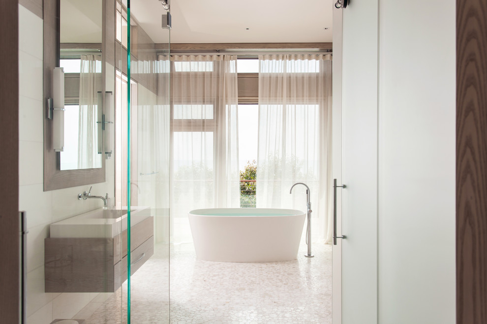 Esempio di una grande stanza da bagno padronale minimalista con lavabo sospeso, top in superficie solida, vasca freestanding, piastrelle beige, pareti beige e pavimento con piastrelle in ceramica