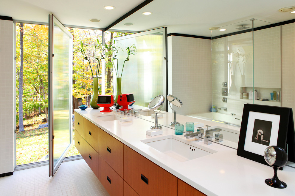 Modelo de cuarto de baño moderno con lavabo bajoencimera, armarios con paneles lisos, puertas de armario de madera oscura y combinación de ducha y bañera