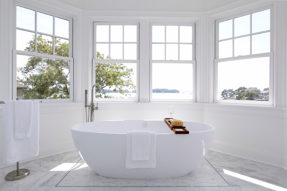 Imagen de cuarto de baño principal minimalista de tamaño medio con bañera exenta, baldosas y/o azulejos grises, baldosas y/o azulejos de piedra y paredes blancas