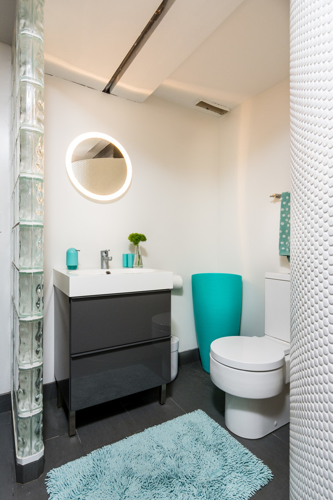 Foto de cuarto de baño contemporáneo con armarios con paneles lisos, puertas de armario grises, sanitario de dos piezas, baldosas y/o azulejos grises, paredes blancas, lavabo tipo consola y espejo con luz