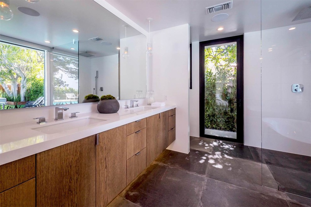 Mid-sized trendy master concrete floor and gray floor bathroom photo in Los Angeles with flat-panel cabinets, dark wood cabinets, a one-piece toilet, white walls, an integrated sink and solid surface countertops