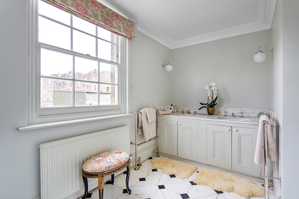 Cette photo montre une salle de bain chic avec un placard avec porte à panneau encastré, des portes de placard grises, un mur gris, un sol en carrelage de porcelaine, un lavabo encastré, un plan de toilette en marbre et un sol multicolore.