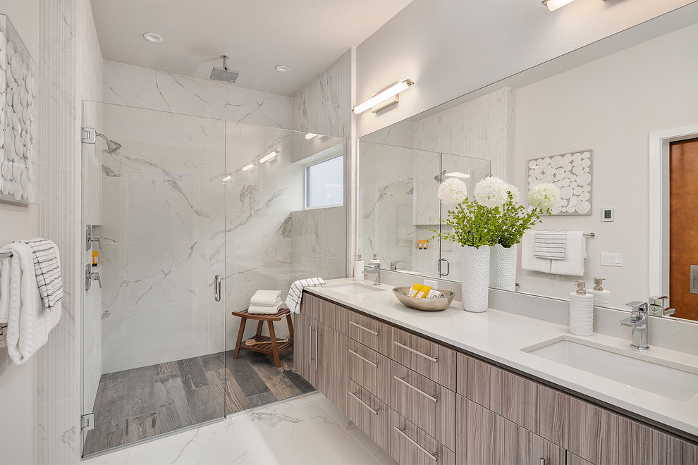 Modern inredning av ett vit vitt badrum, med släta luckor, grå skåp, en dusch i en alkov, vita väggar, ett undermonterad handfat, vitt golv och dusch med gångjärnsdörr