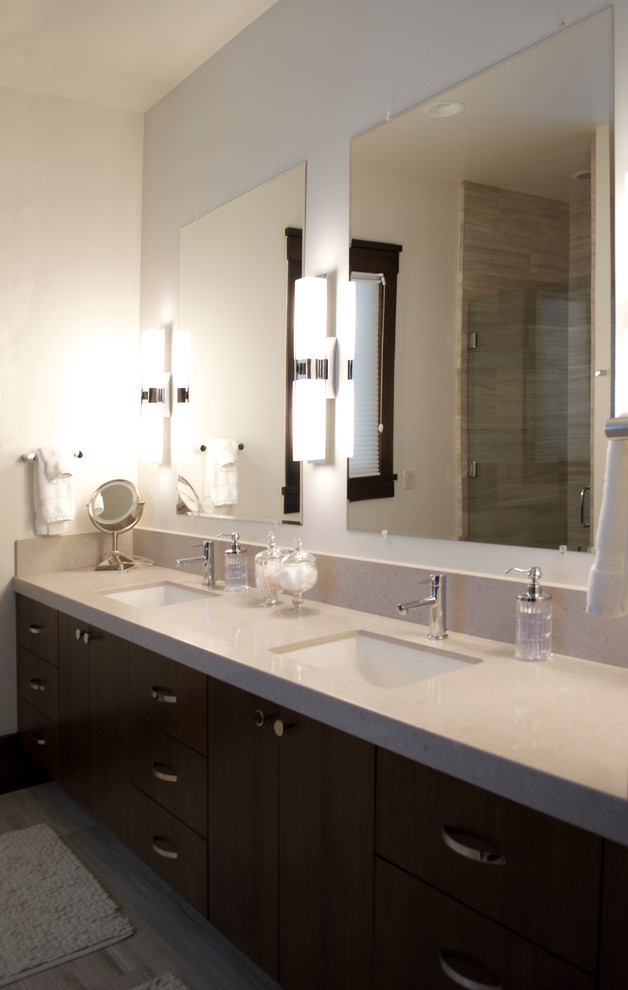 This is an example of a medium sized contemporary ensuite bathroom in Salt Lake City with dark wood cabinets, a submerged bath, grey tiles, stone tiles, white walls, a submerged sink, flat-panel cabinets, an alcove shower, laminate floors, quartz worktops, brown floors, a hinged door and beige worktops.