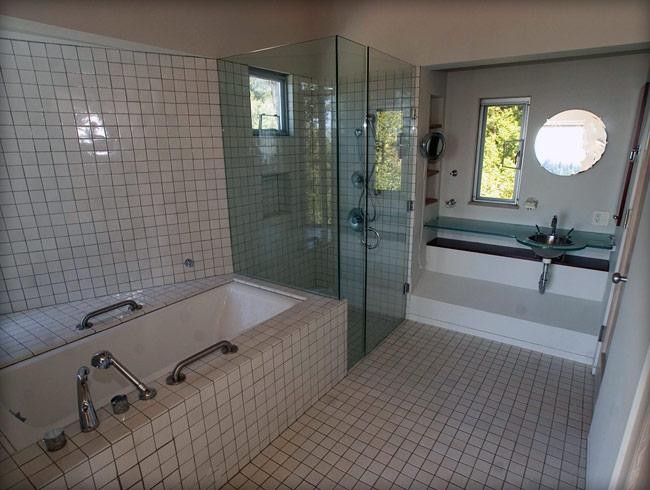 На фото: большая главная ванная комната в стиле модернизм с стеклянной столешницей, полновстраиваемой ванной, душем без бортиков, бежевой плиткой, бежевыми стенами и полом из керамогранита с