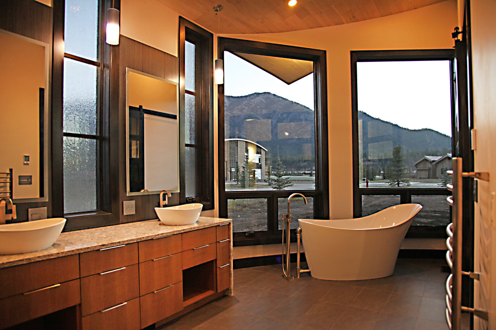 Exemple d'une grande salle de bain principale moderne en bois brun avec un placard à porte plane, une baignoire indépendante, un mur beige, un sol en bois brun, une vasque, un plan de toilette en granite et un sol marron.