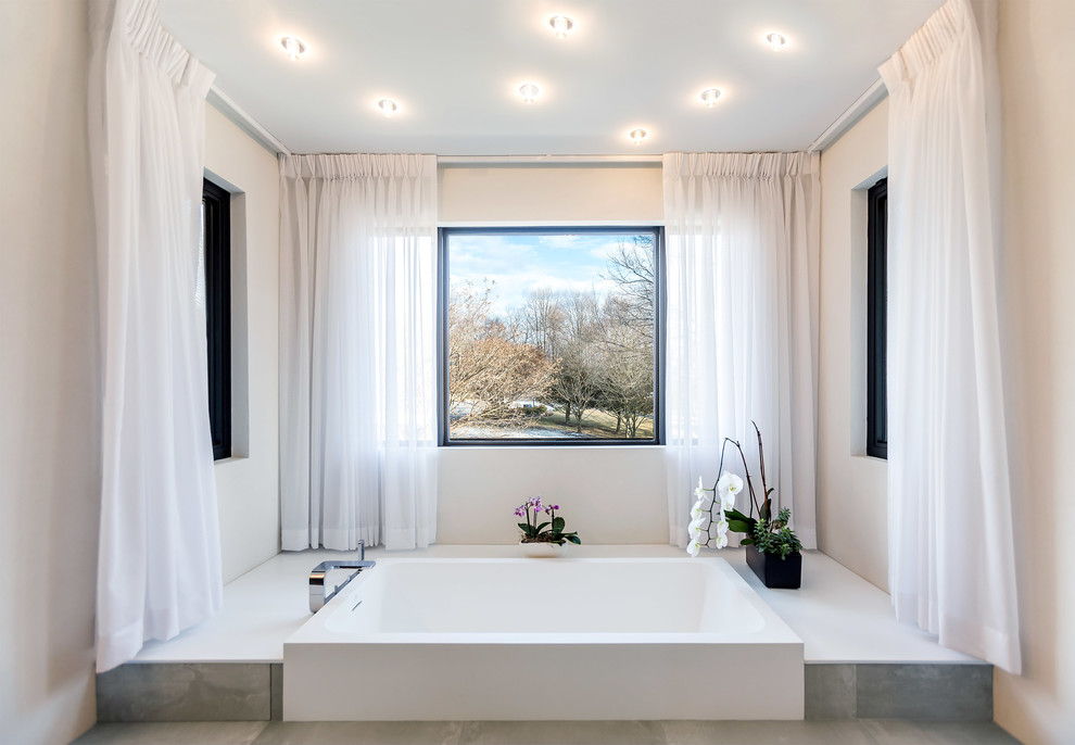Diseño de cuarto de baño principal contemporáneo con paredes blancas, suelo de baldosas de porcelana, suelo gris y bañera japonesa