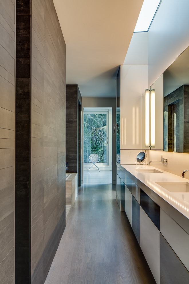 Modelo de cuarto de baño moderno con lavabo bajoencimera, armarios con paneles lisos, encimera de cuarzo compacto y encimeras blancas