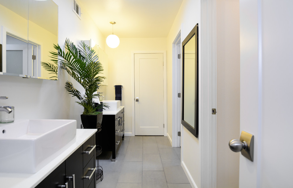 This is an example of a large modern family bathroom in Los Angeles with flat-panel cabinets, black cabinets, grey tiles, porcelain tiles, white walls, porcelain flooring, a vessel sink and solid surface worktops.