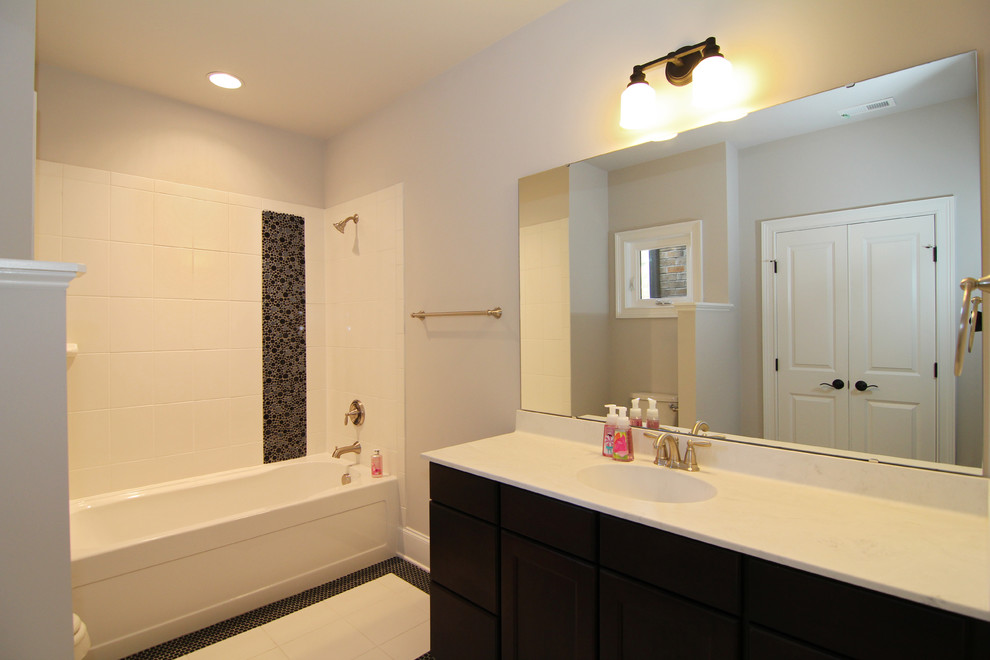 Example of a large trendy kids' white tile and mosaic tile ceramic tile bathroom design in Raleigh with recessed-panel cabinets, dark wood cabinets, a one-piece toilet, gray walls, an integrated sink and solid surface countertops