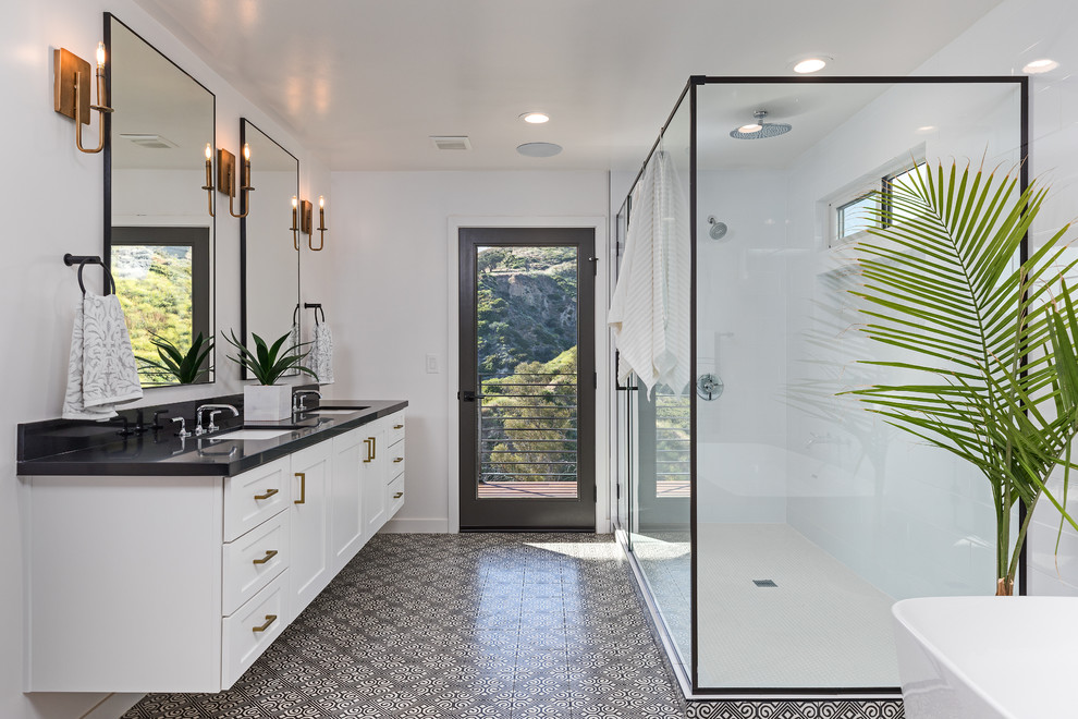 Classic ensuite bathroom in DC Metro with shaker cabinets, white cabinets, a freestanding bath, an alcove shower, white tiles, white walls, a submerged sink, black floors, a hinged door and black worktops.