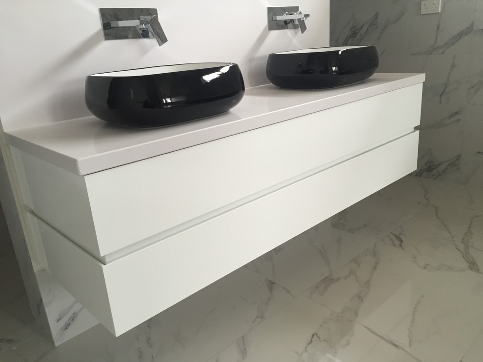 Foto di una stanza da bagno design con ante lisce, ante bianche, piastrelle di marmo, pareti bianche, pavimento in marmo e lavabo a bacinella