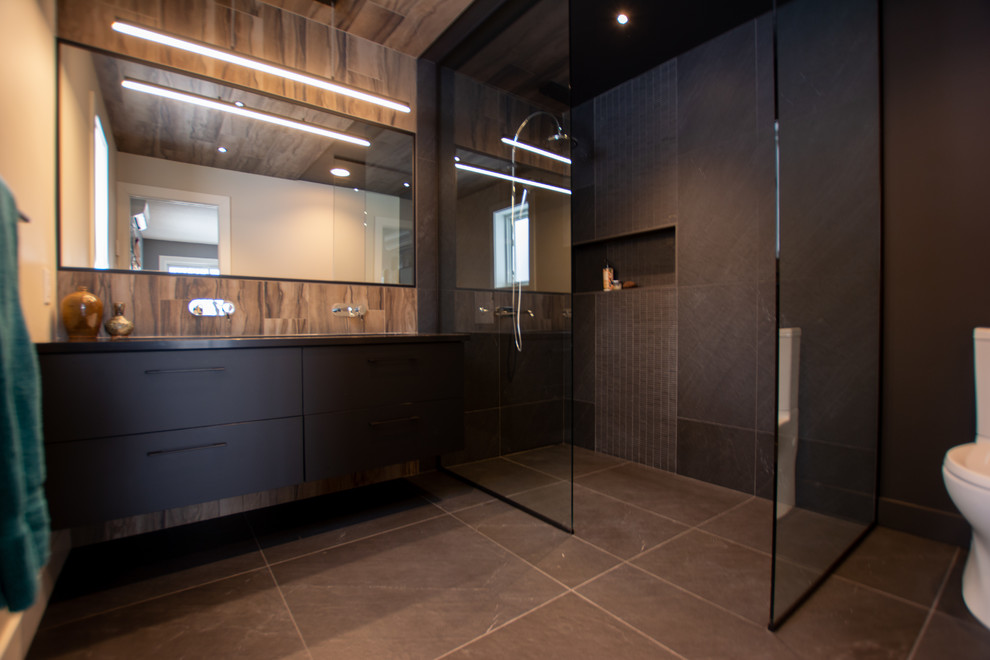 Diseño de cuarto de baño moderno de tamaño medio con sanitario de una pieza, paredes negras, suelo de baldosas de cerámica, lavabo suspendido, suelo negro, armarios con paneles lisos, puertas de armario negras, ducha abierta, baldosas y/o azulejos beige, baldosas y/o azulejos marrones, baldosas y/o azulejos de porcelana, aseo y ducha, encimera de cuarzo compacto, ducha abierta y encimeras negras