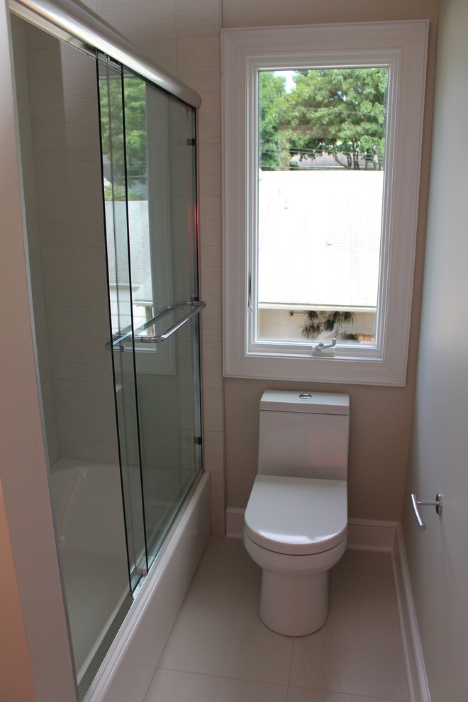 Modern inredning av ett mellanstort badrum för barn, med en dusch/badkar-kombination, en toalettstol med hel cisternkåpa, beige kakel, porslinskakel, beige väggar och klinkergolv i porslin