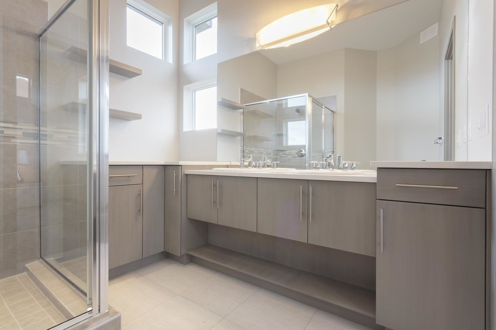 Idée de décoration pour une grande salle de bain principale minimaliste avec un lavabo posé, un placard à porte plane, des portes de placard grises, un plan de toilette en surface solide, une douche d'angle, un carrelage gris et un mur blanc.