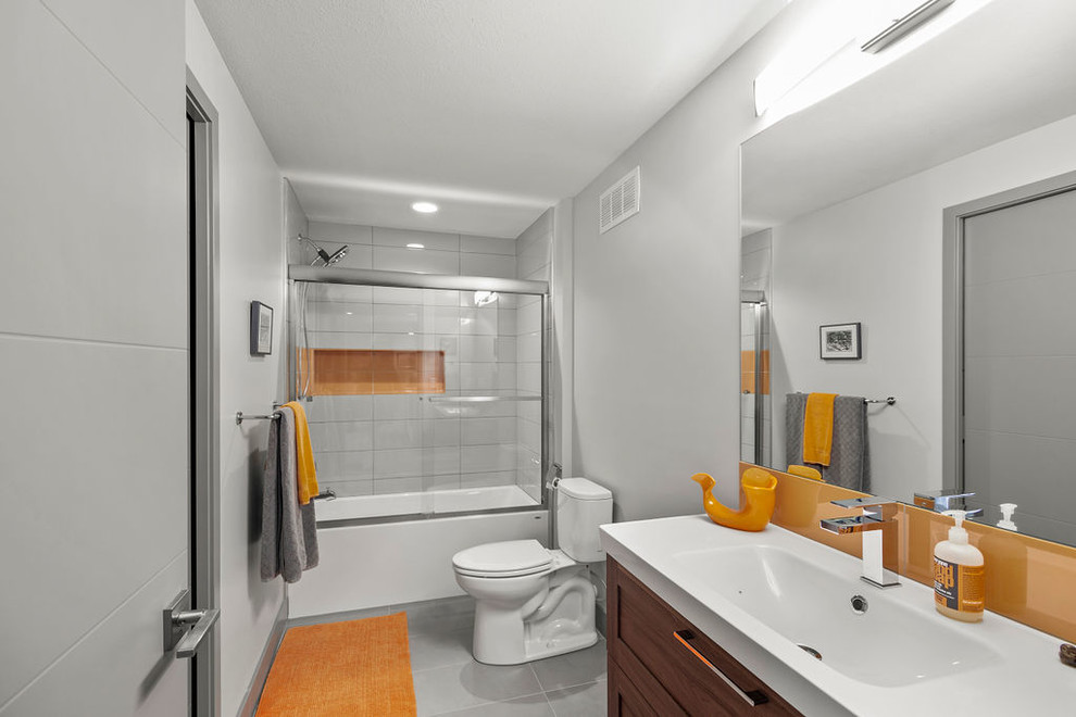 Идея дизайна: большая ванная комната в современном стиле с фасадами с утопленной филенкой, светлыми деревянными фасадами, ванной в нише, душем в нише, раздельным унитазом, серыми стенами, душевой кабиной, накладной раковиной, столешницей из искусственного камня, серым полом, душем с раздвижными дверями, белой столешницей и полом из керамогранита