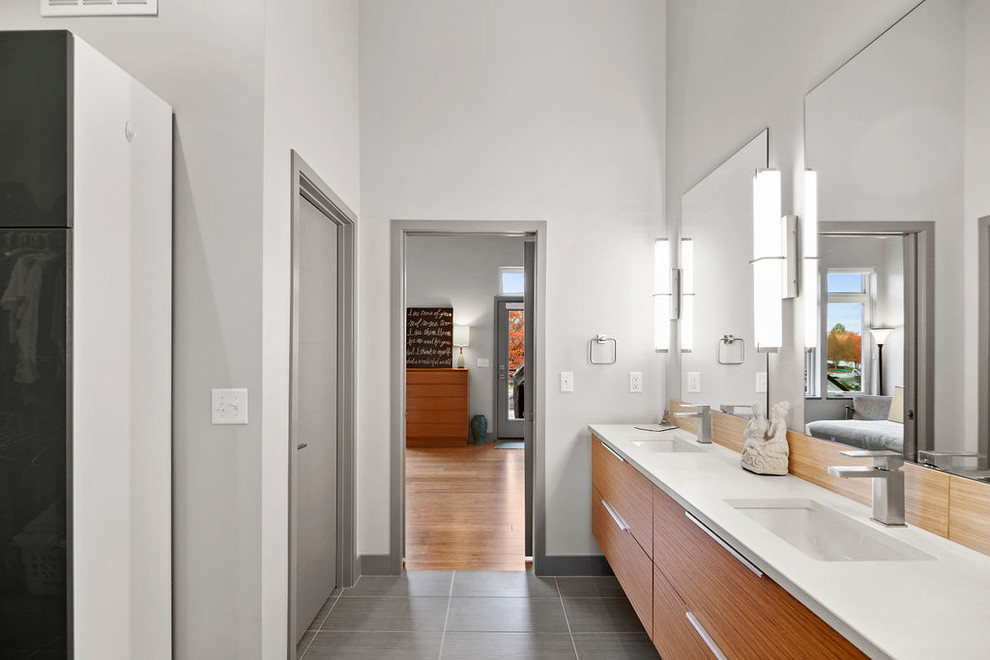 Источник вдохновения для домашнего уюта: большая главная ванная комната в современном стиле с плоскими фасадами, светлыми деревянными фасадами, душем в нише, раздельным унитазом, серыми стенами, накладной раковиной, столешницей из искусственного кварца, серым полом, душем с распашными дверями, белой столешницей и полом из керамогранита