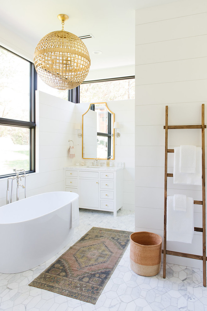 Diseño de cuarto de baño tradicional renovado de tamaño medio con puertas de armario blancas, bañera exenta, encimera de mármol, armarios estilo shaker, paredes blancas, lavabo bajoencimera, suelo gris y encimeras blancas