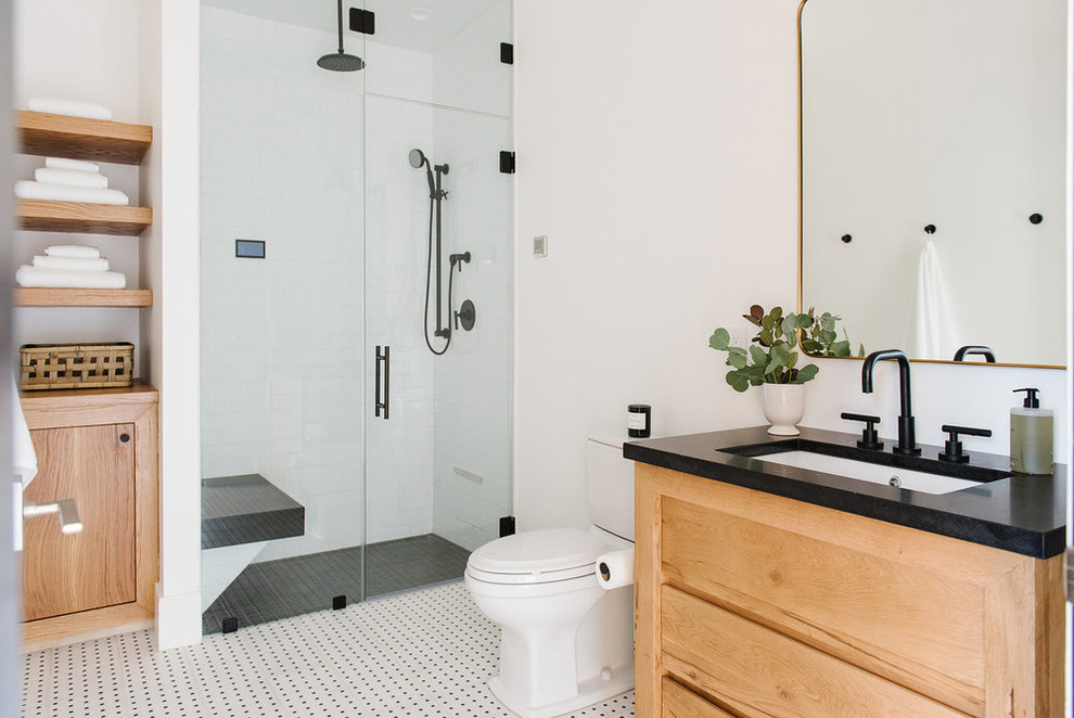 Exemple d'une salle de bain nature en bois clair de taille moyenne avec un carrelage blanc, des carreaux de céramique, un mur blanc, une cabine de douche à porte battante et un plan de toilette noir.