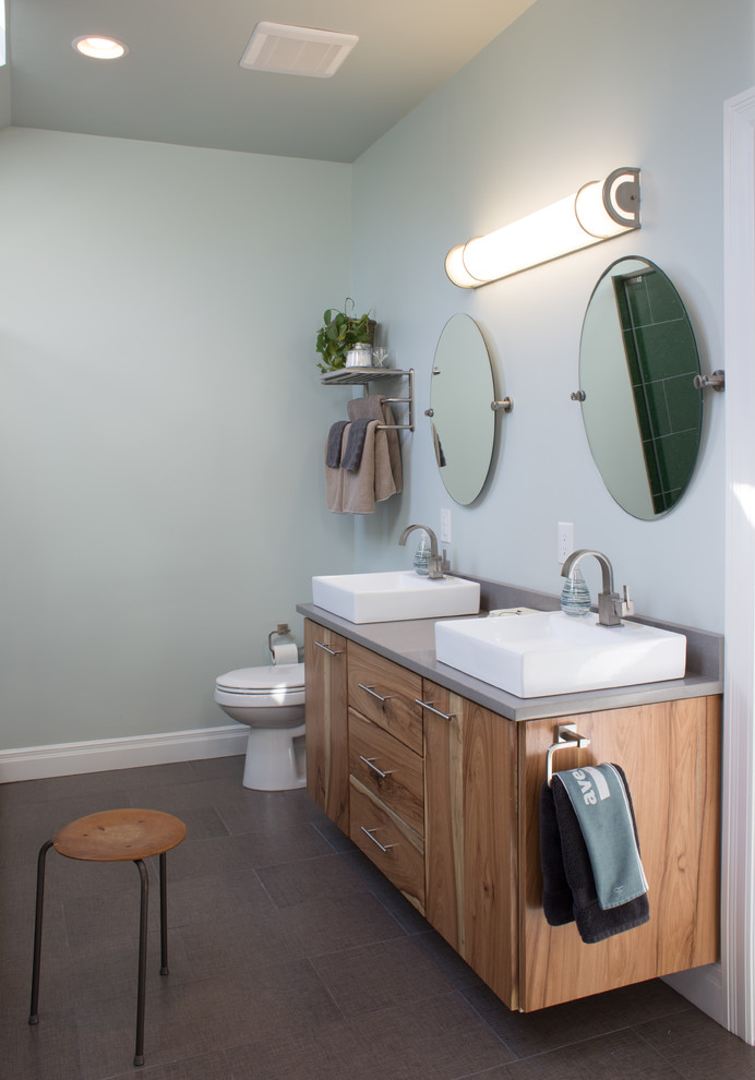 Idéer för att renovera ett mellanstort funkis en-suite badrum, med ett fristående handfat, släta luckor, skåp i mellenmörkt trä, bänkskiva i kvarts, ett fristående badkar, en toalettstol med separat cisternkåpa, grå kakel, keramikplattor, gröna väggar och klinkergolv i keramik