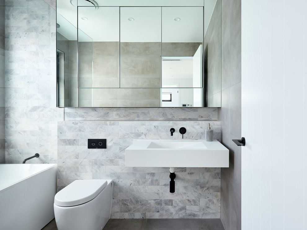 Esempio di una stanza da bagno minimal con vasca ad alcova, piastrelle grigie, lavabo integrato, pavimento grigio e top bianco
