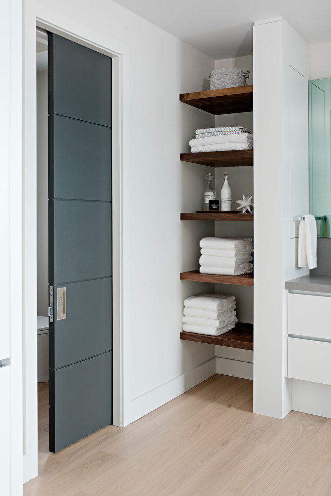 Modern inredning av ett mycket stort grå grått en-suite badrum, med släta luckor, vita skåp, en kantlös dusch, en vägghängd toalettstol, grå kakel, porslinskakel, vita väggar, ljust trägolv, ett undermonterad handfat och bänkskiva i kvarts