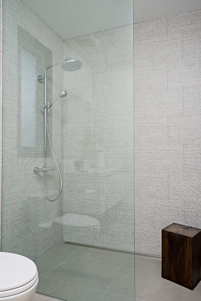 Walk-in shower - mid-sized contemporary gray tile and porcelain tile light wood floor walk-in shower idea in Toronto with flat-panel cabinets, white cabinets, a wall-mount toilet, white walls, an undermount sink, quartz countertops and gray countertops